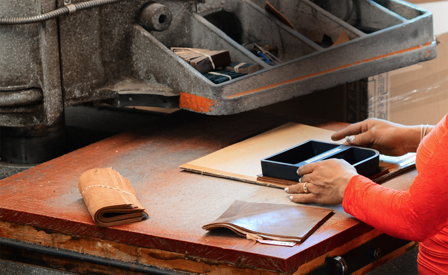 Smaller leather pieces are die-cut by a woman at the Schott factory